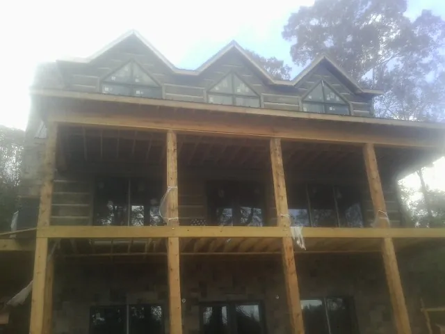 Dormers and porch framing on a large log home under construction — Roof Coating work by our crew in La Ward
