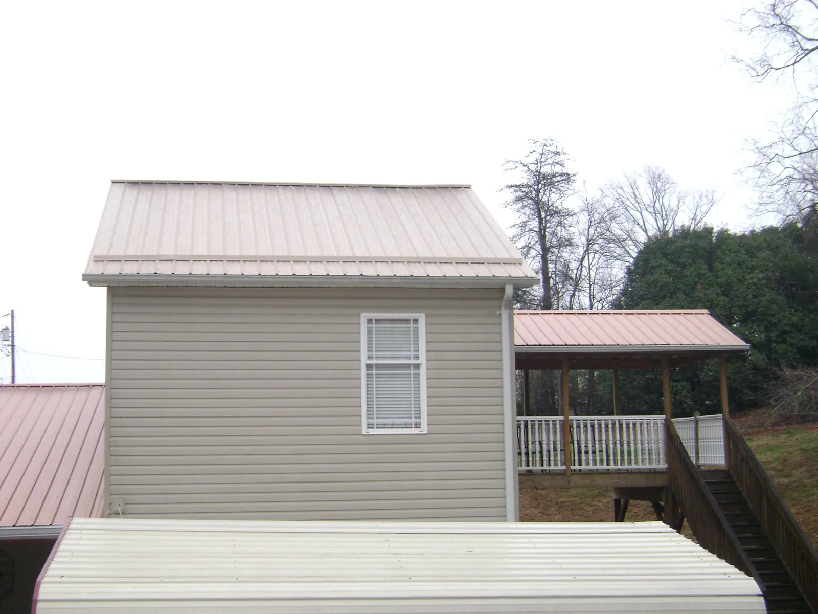 Tan metal roofs on a two story addition and attached porch, from a Roof Replacement job in La Ward