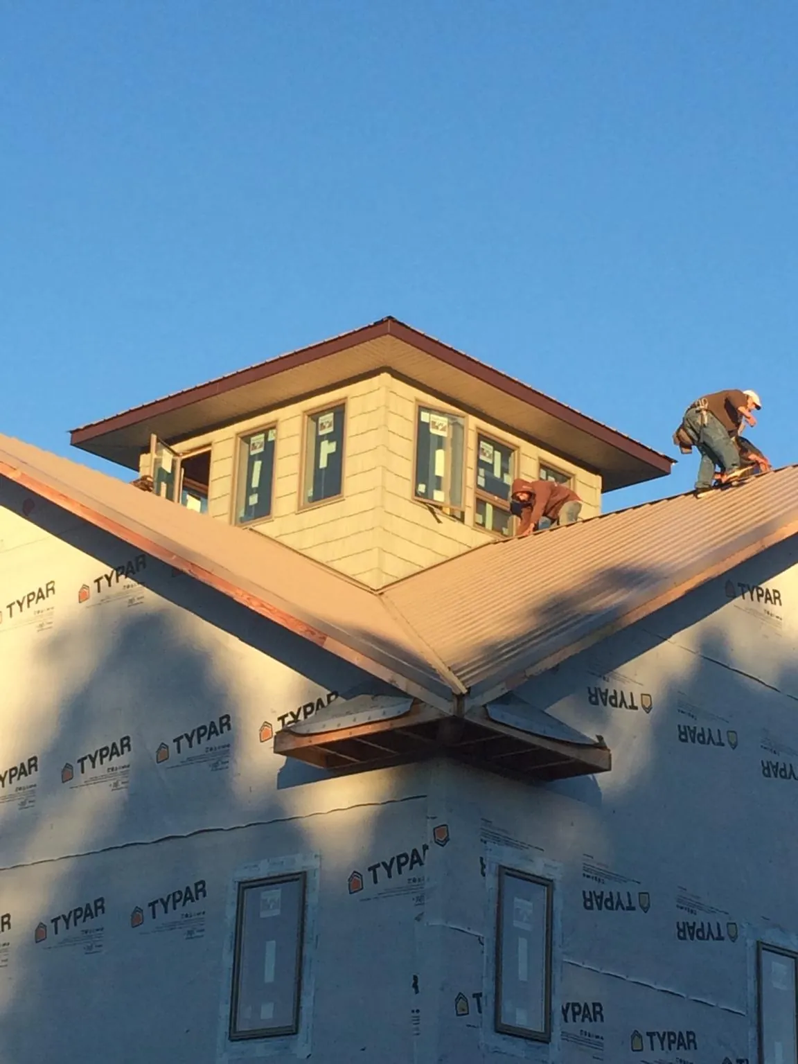 Roofers working around a rooftop cupola on a new metal roof at sunset — Roof Waterproofing in La Ward by Roofing Brothers